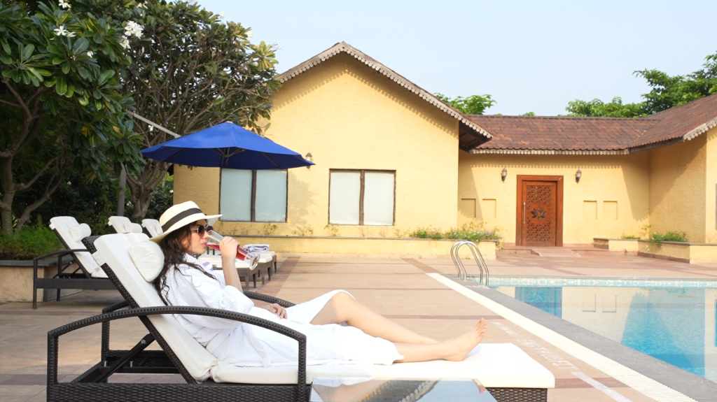 Guest relaxing by the poolside at WelcomHeritage Tadoba Vanya Villas, enjoying a serene luxury experience surrounded by greenery